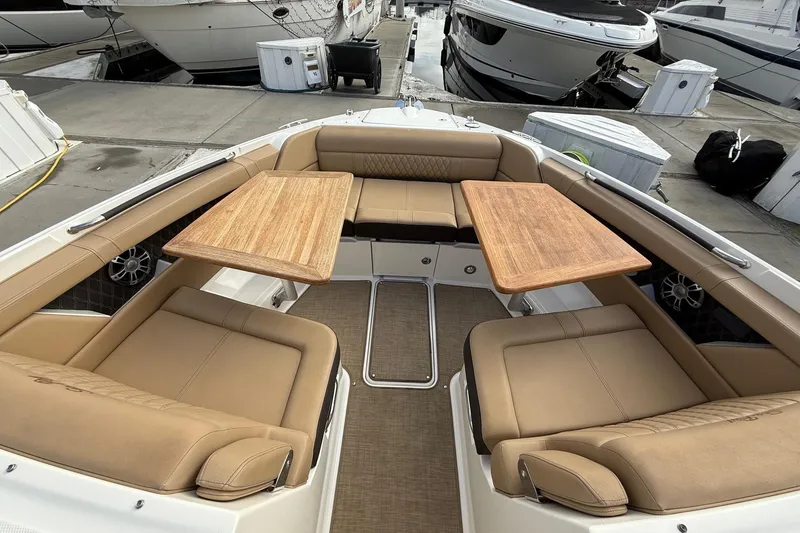 Slide: The Image of Luxurious seating area on 2023 Sea Ray SLX 350 boat with wooden tables. - 33