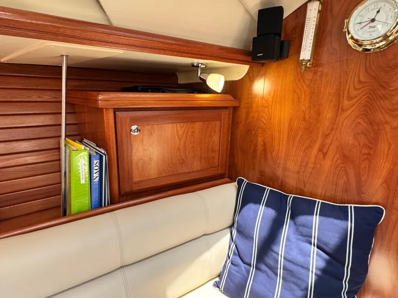Slide: The Image of Interior of a 2009 Hunter 50 Center Cockpit with wood paneling and blue-striped cushions. - 48
