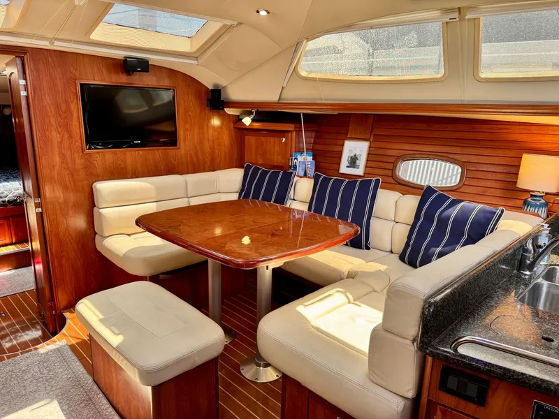 Slide: The Image of The interior of a 2009 Hunter 50 Center Cockpit features a cozy seating area with a wooden table and cushioned benches. - 38