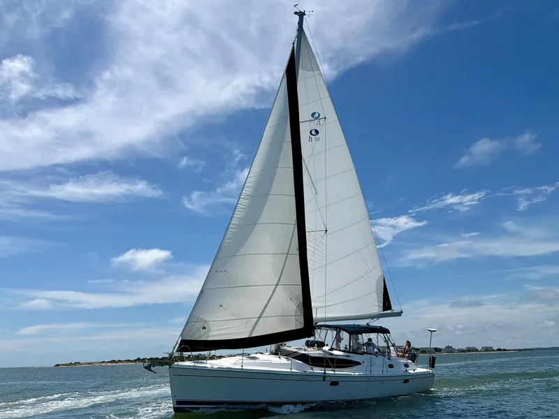 Slide: The Image of 2009 Hunter 50 Center Cockpit sailboat on the water with white sails and a blue sky. - 4