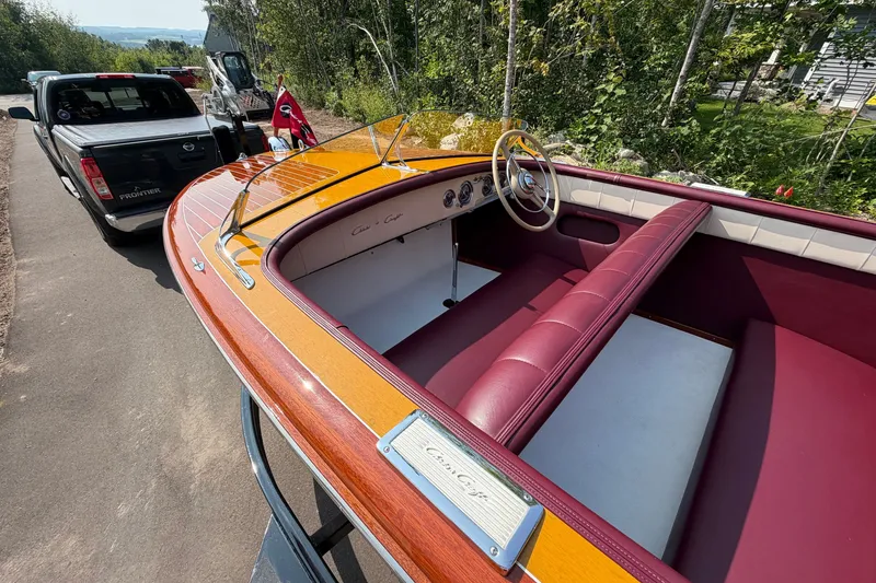 Slide: The Image of 1953 Chris Craft Riviera boat with vintage wooden design and maroon interior, parked near a truck. - 14