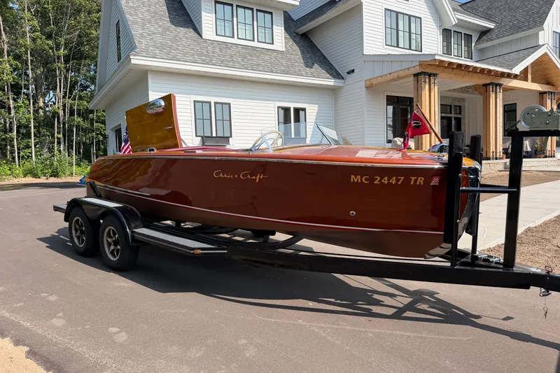 Slide: The Image of 1953 Chris Craft Riviera boat on trailer, parked in front of a modern house. - 28