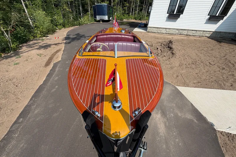 Slide: The Image of 1953 Chris Craft Riviera boat with polished wood finish on a driveway. - 9