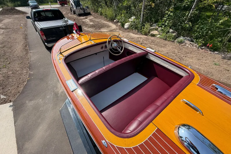 Slide: The Image of 1953 Chris Craft Riviera boat with polished wood finish and maroon interior, hitched to a truck. - 15