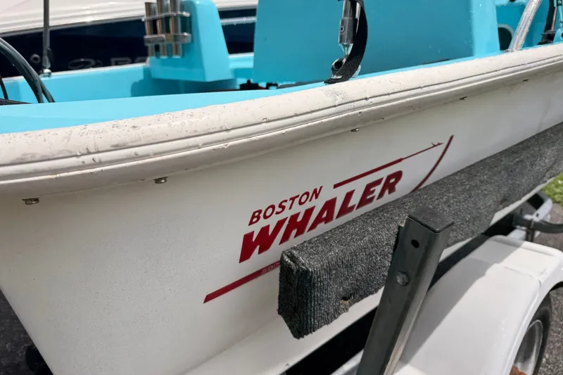 Slide: The Image of 2009 Boston Whaler 130 Sport boat on trailer, showcasing logo and blue interior. - 19