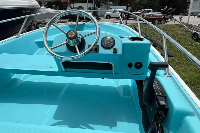 Slide: The Image of 2009 Boston Whaler 130 Sport boat interior with turquoise dashboard and steering wheel. - 14