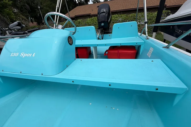 Slide: The Image of 2009 Boston Whaler 130 Sport boat interior, featuring turquoise seating and steering wheel. - 17