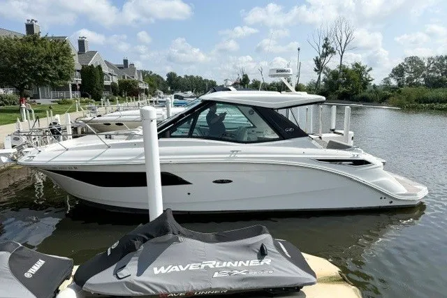 Slide: The Image of 2022 Sea Ray Sundancer 320 docked at a marina, surrounded by calm waters and greenery. - 3