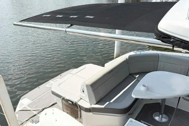 Slide: The Image of 2022 Sea Ray Sundancer 320 boat with seating area and table, docked by the water. - 5