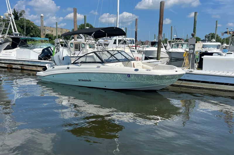 Slide: The Image of 2023 Stingray 191 DC boat docked at marina under blue sky. - 8