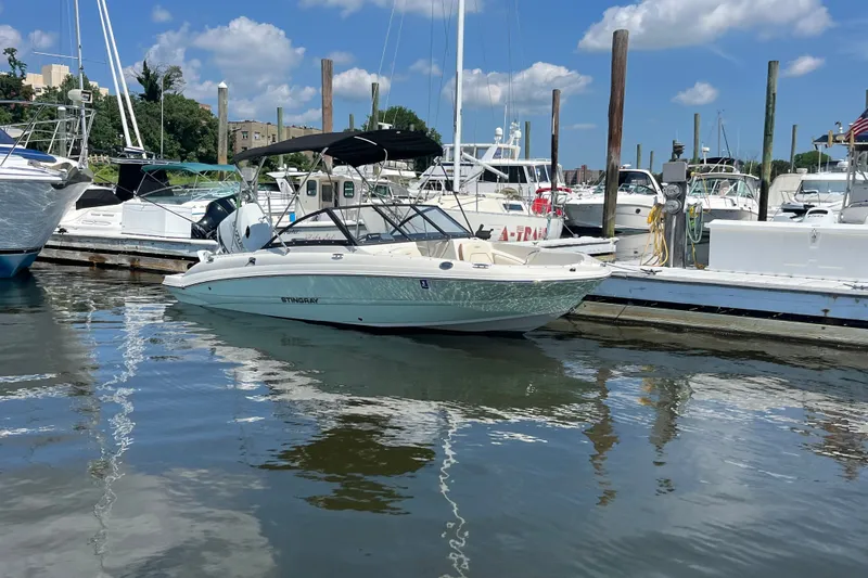 Slide: The Image of 2023 Stingray 191 DC boat docked at a marina under a clear blue sky. - 9