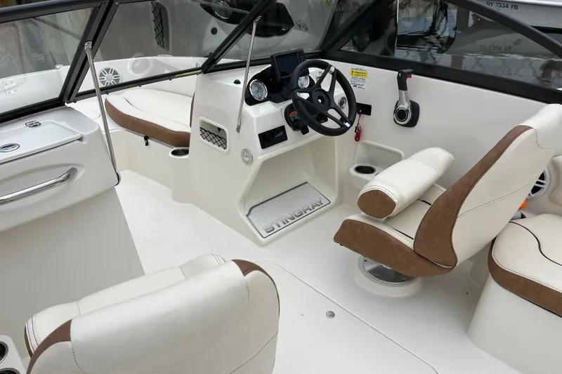 Slide: The Image of 2023 Stingray 191 DC boat interior with white and brown seating, steering wheel, and dashboard. - 16