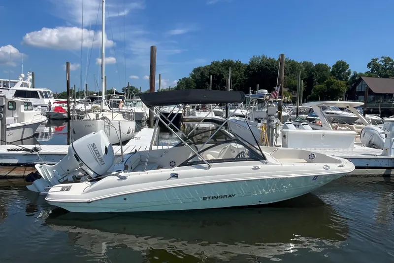 Slide: The Image of 2023 Stingray 191 DC boat docked at marina, featuring Suzuki outboard motor. - 1