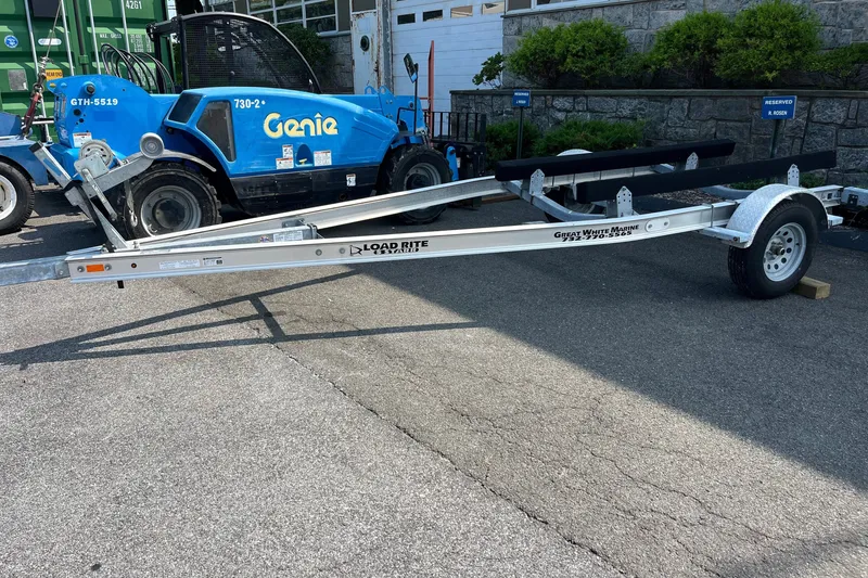 Slide: The Image of Trailer for 2023 Stingray 191 DC boat, parked on pavement near blue Genie lift. - 24