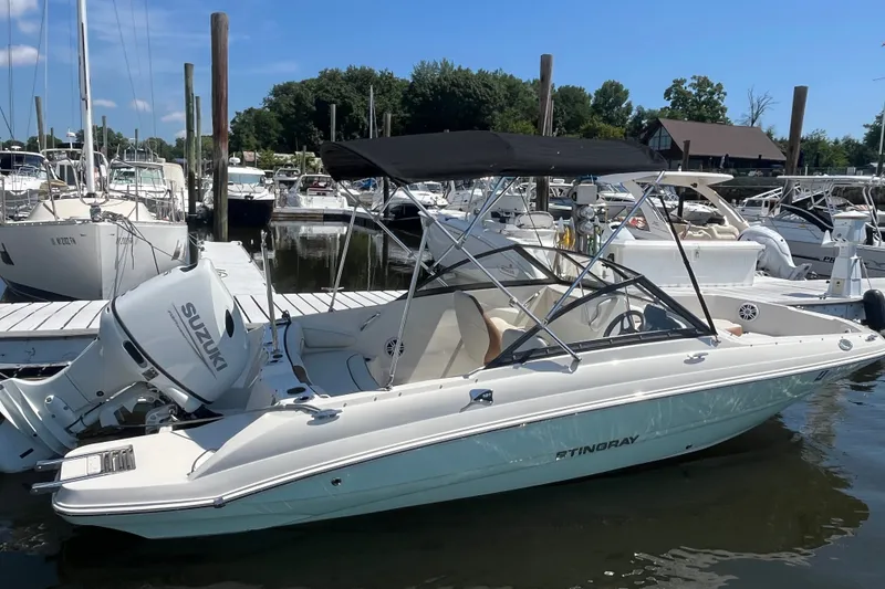 Slide: The Image of 2023 Stingray 191 DC boat docked, featuring Suzuki outboard motor and black canopy. - 2