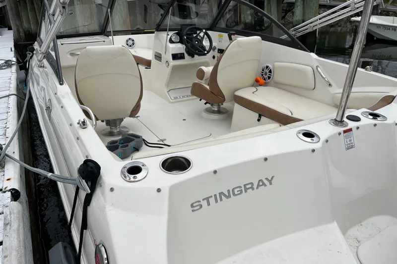 Slide: The Image of 2023 Stingray 191 DC boat interior with seating and steering wheel at dock. - 15