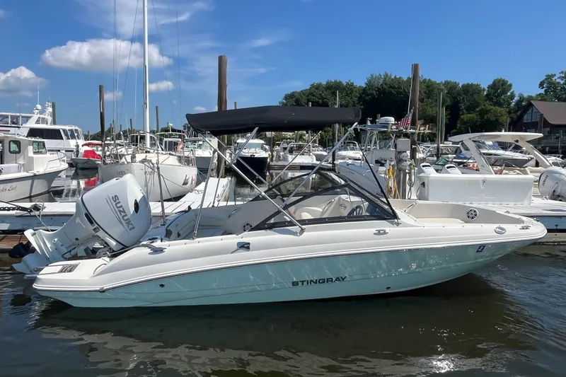 The Image of 2023 Stingray 191 DC boat docked in marina, featuring Suzuki outboard motor. - 0