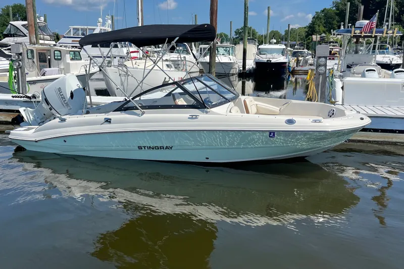 Slide: The Image of 2023 Stingray 191 DC boat docked at a marina with a Suzuki outboard motor. - 6