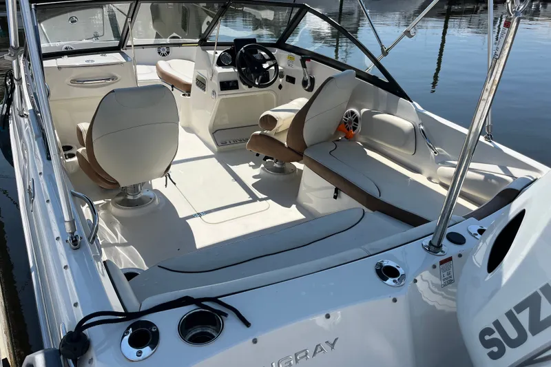 Slide: The Image of 2023 Stingray 191 DC boat interior with seating and steering, docked on calm water. - 14