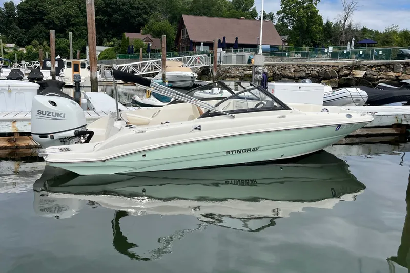 Slide: The Image of 2023 Stingray 191 DC boat docked with Suzuki outboard motor, reflecting on calm water. - 11