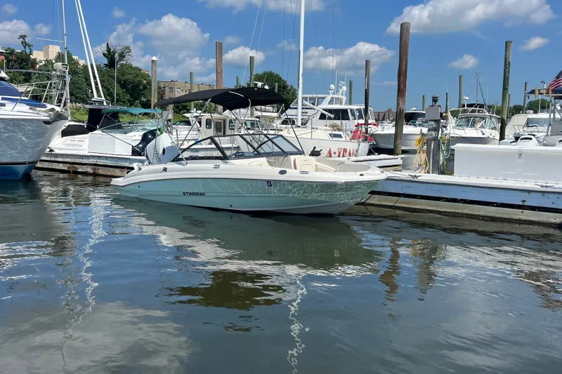 Slide: The Image of 2023 Stingray 191 DC boat docked in a marina under a clear blue sky. - 7