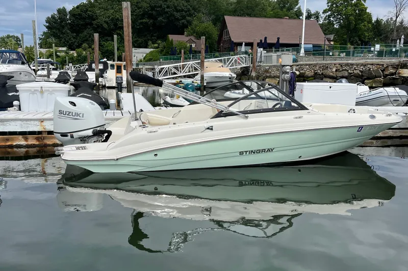Slide: The Image of 2023 Stingray 191 DC boat docked with Suzuki outboard motor in a marina. - 10