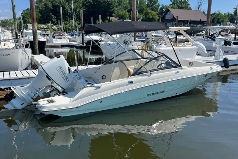 Slide: The Image of 2023 Stingray 191 DC boat docked in a marina with Suzuki outboard motor. - 5