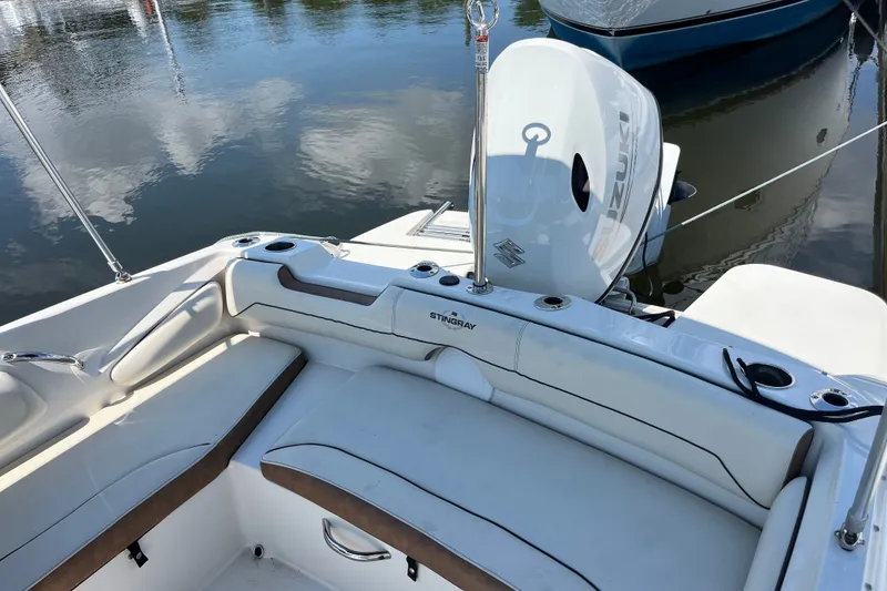 Slide: The Image of 2023 Stingray 191 DC boat interior with Suzuki outboard motor, docked on calm water. - 21