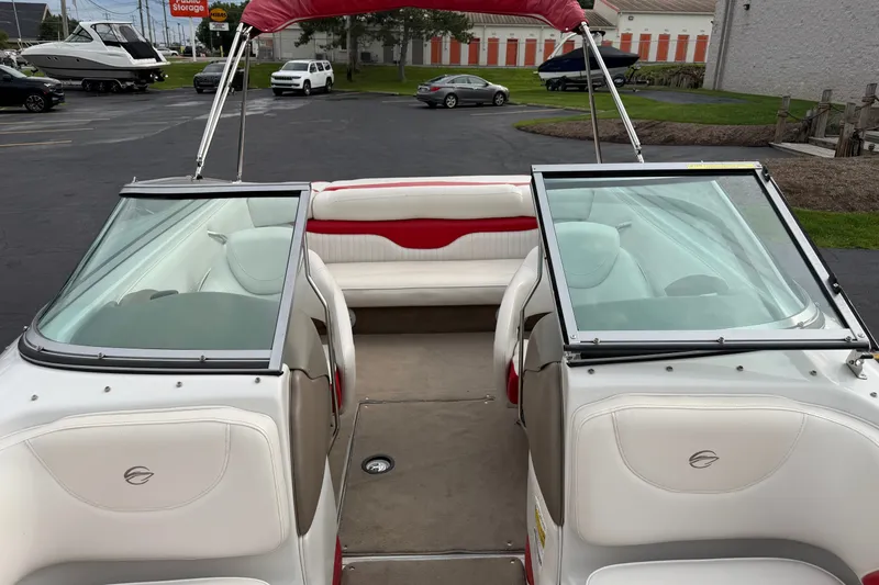 Slide: The Image of 2011 Crownline 21 SS boat interior with white and red seating, parked outdoors. - 8