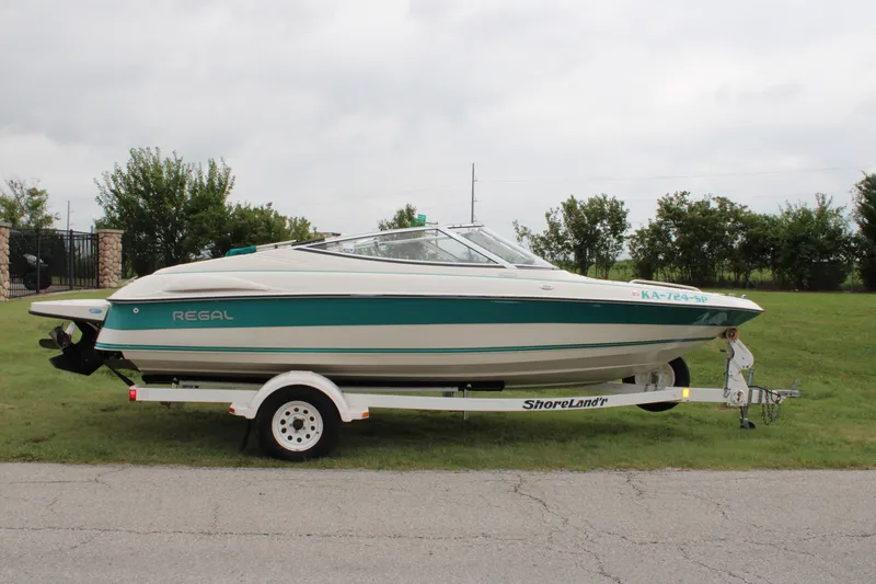 The Image of 1995 Regal 2000 ES boat on trailer, parked on grass, side view. - 0