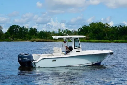 Slide: The Image of 2022 Sea Hunt Ultra 265SE boat on a serene lake with lush greenery. - 3
