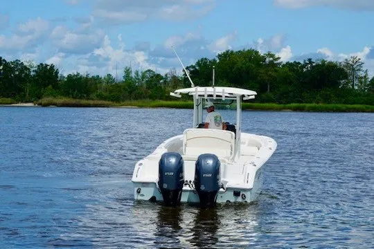 Slide: The Image of 2022 Sea Hunt Ultra 265SE boat cruising on a calm lake with twin engines. - 2