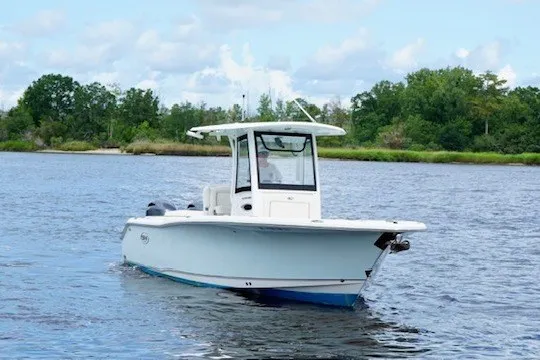 Slide: The Image of 2022 Sea Hunt Ultra 265SE boat cruising on a serene lake with lush greenery. - 4