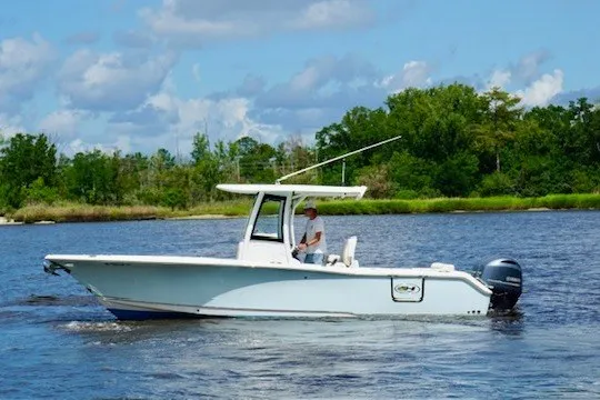 The Image of 2022 Sea Hunt Ultra 265SE boat cruising on a scenic river with lush greenery. - 0