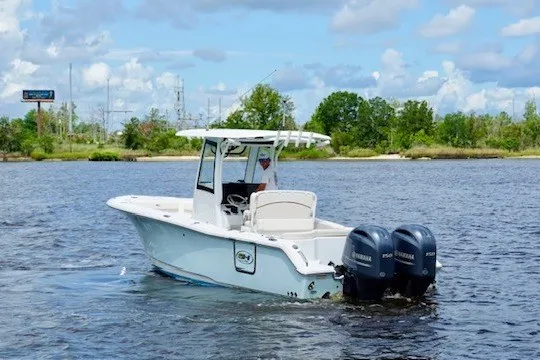Slide: The Image of 2022 Sea Hunt Ultra 265SE boat on a calm lake with twin engines. - 1