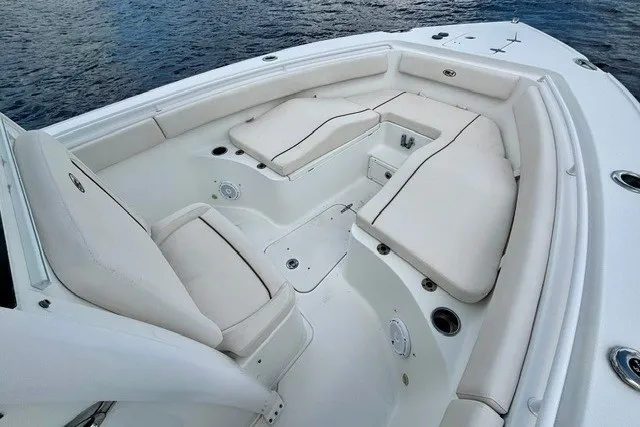 Slide: The Image of 2022 Sea Hunt Ultra 265SE boat with spacious white seating area on calm water. - 10