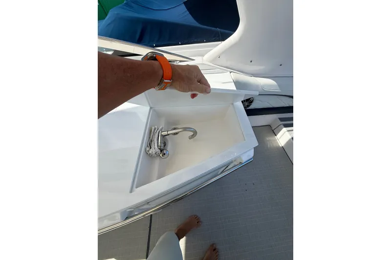 Slide: The Image of 2022 Regal 33 OBX boat sink with cover being lifted, showcasing sleek design. - 13