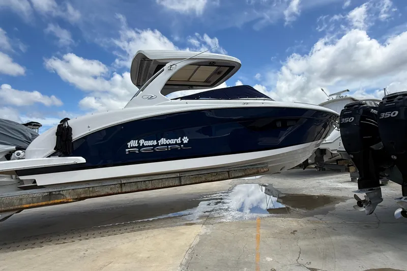 The Image of 2022 Regal 33 OBX boat on a lift, under a partly cloudy sky. - 0