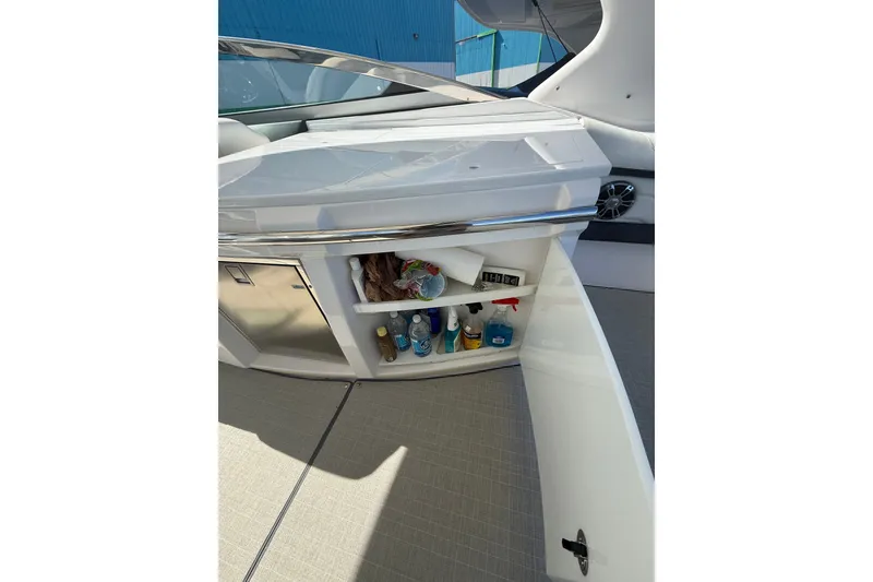Slide: The Image of 2022 Regal 33 OBX boat interior storage compartment with cleaning supplies and beverages. - 15
