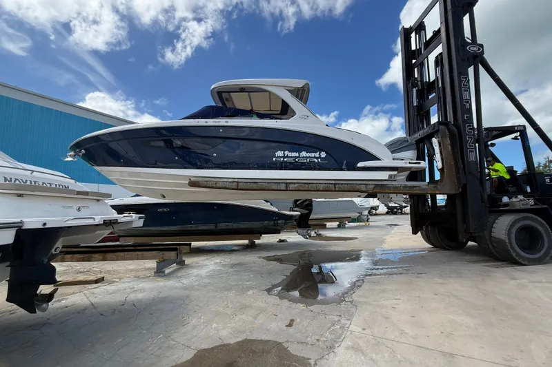 Slide: The Image of 2022 Regal 33 OBX boat lifted by forklift in marina setting. - 3