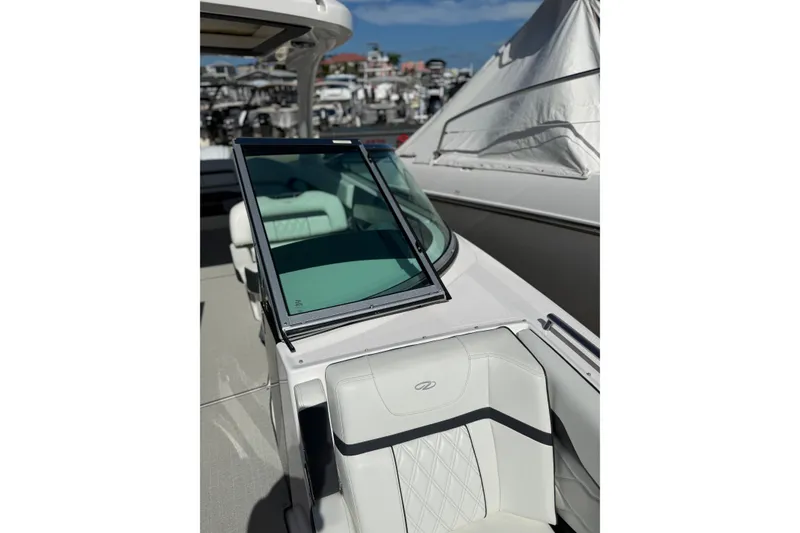 Slide: The Image of 2022 Regal 33 OBX boat with sleek seating and windshield, docked under clear skies. - 30