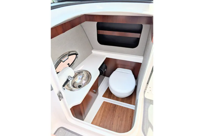Slide: The Image of 2020 Chaparral 297 SSX boat interior with compact bathroom, sink, and wooden flooring. - 8