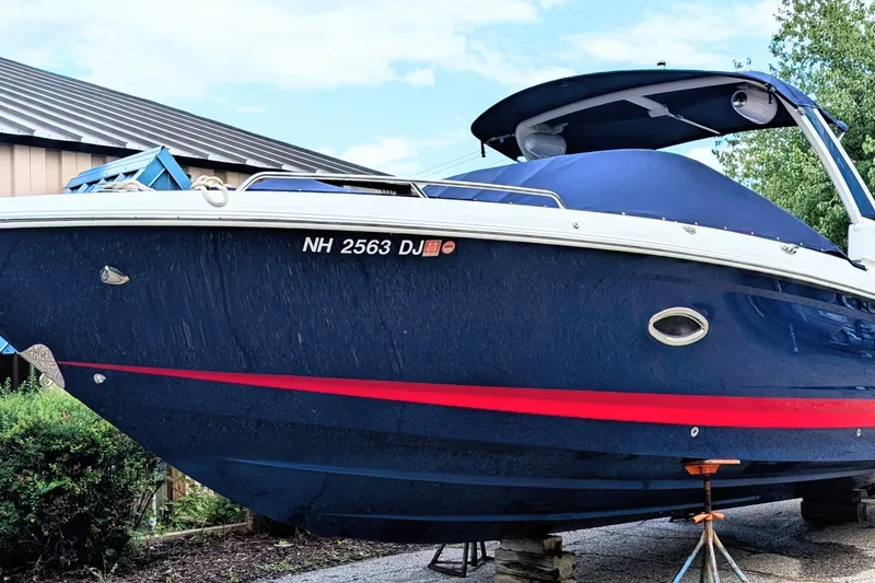 Slide: The Image of 2020 Chaparral 297 SSX boat with blue hull and red stripe, docked outdoors. - 0
