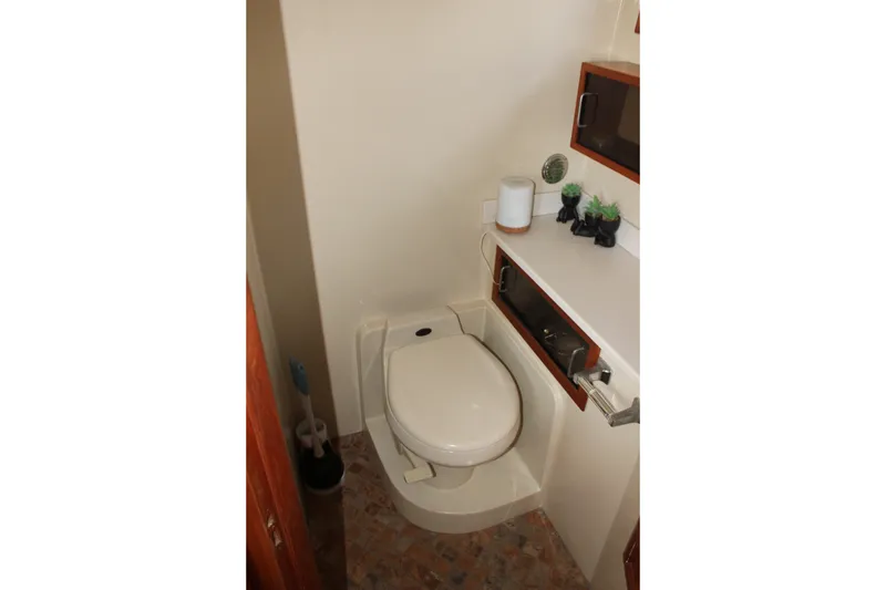 Slide: The Image of Bathroom interior of 1989 Californian 55 Cockpit Motor Yacht with toilet and storage shelves. - 32