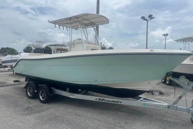 Slide: The Image of 2023 Cobia 237 Center Console boat on trailer, displayed outdoors under cloudy sky. - 1