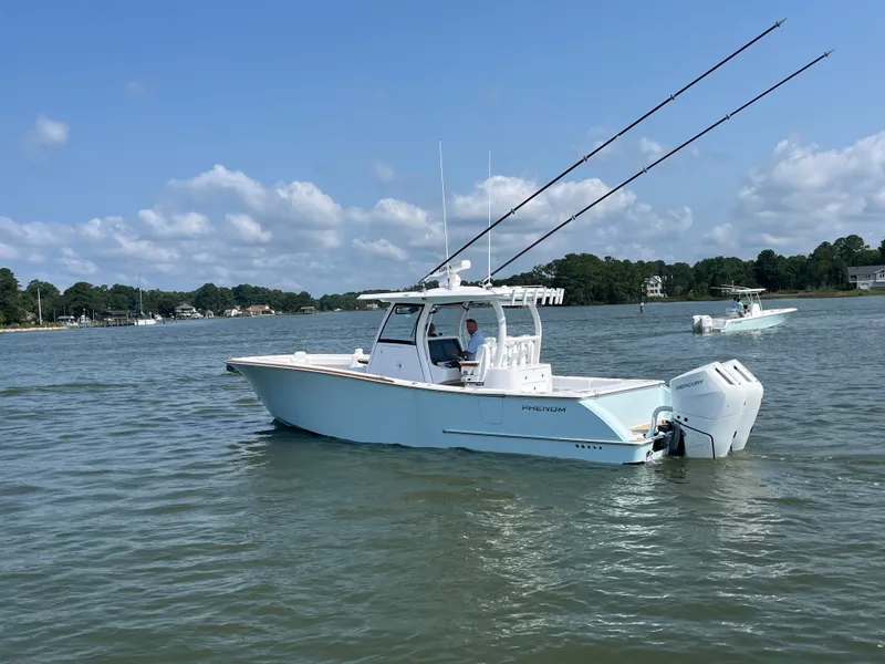 Slide: The Image of Phenom 34 boat on calm water with two fishing rods and an outboard motor. - 4