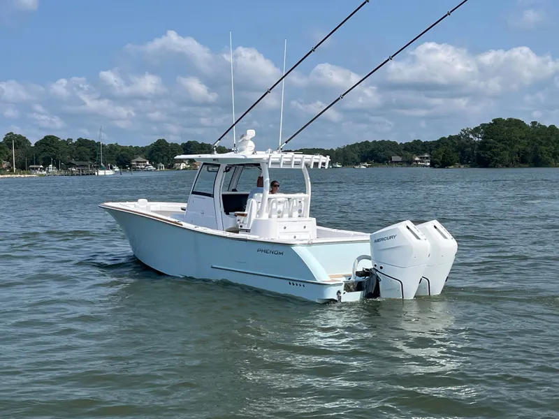 Slide: The Image of The image shows a 2026 Phenom 34 boat on calm water with two outboard engines. - 1