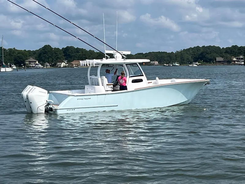 Slide: The Image of A 2026 Phenom 34 boat on calm water with twin outboard engines and a covered helm console. - 6