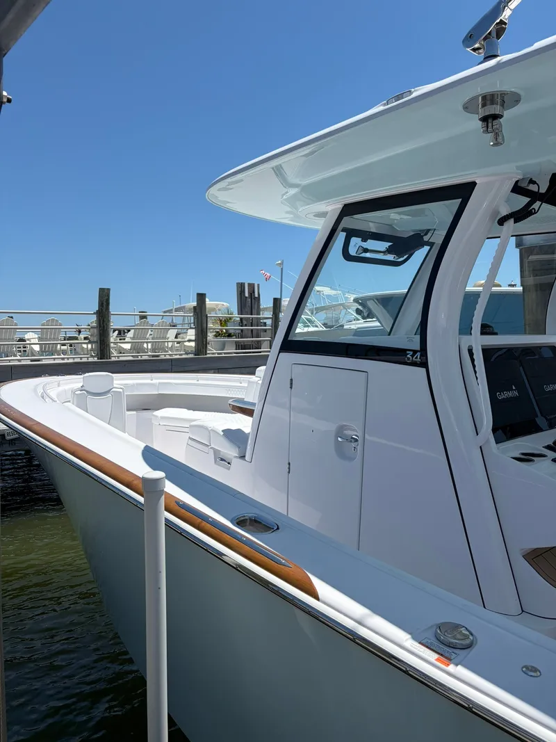 Slide: The Image of A sleek, modern boat with a white hull and wood accents, docked on a sunny day. - 26