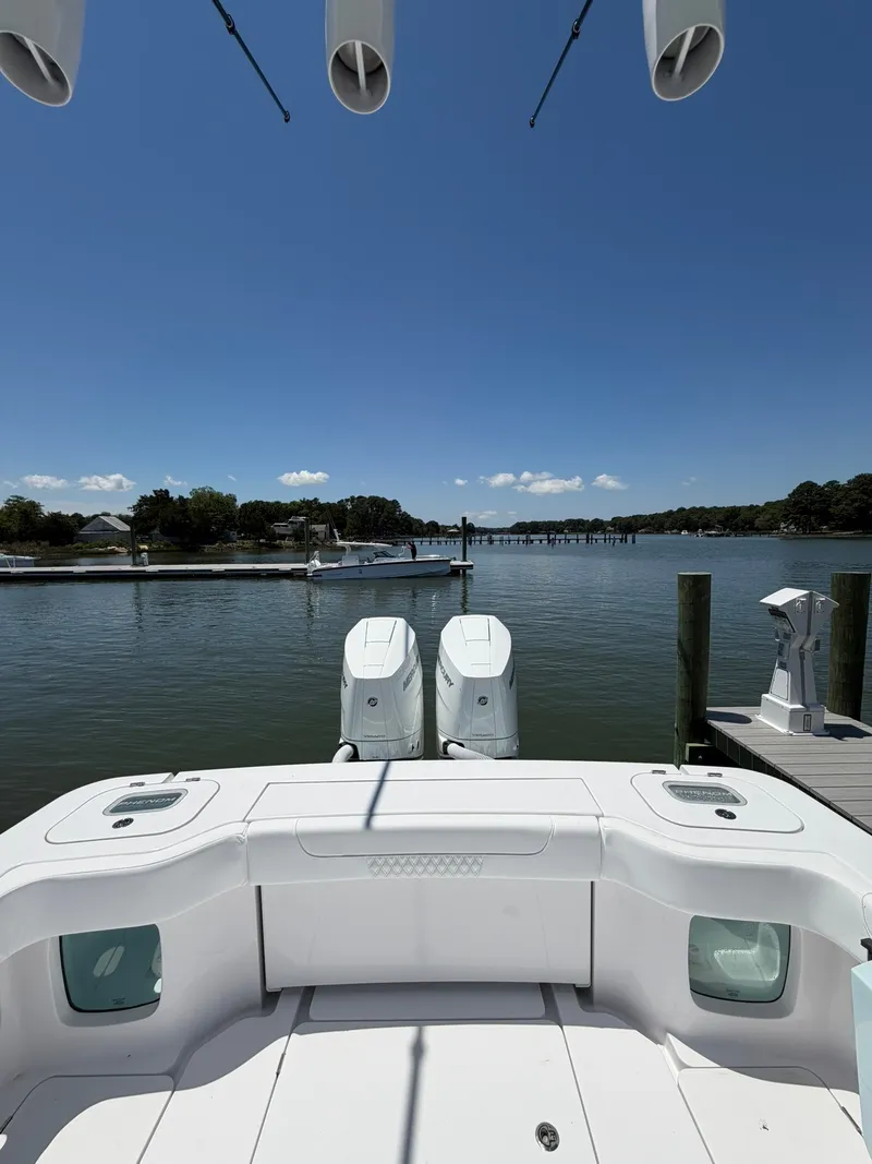Slide: The Image of Aft view of a Phenom 34 boat with twin outboard engines, docked on calm waters. - 21